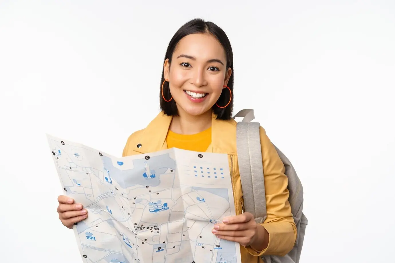 Tourismus und Rucksackreisen: Lächelndes asiatisches Mädchen mit Karte und Rucksack, Touristin auf der Suche nach dem Weg, reisend, vor weißem Hintergrund stehend.